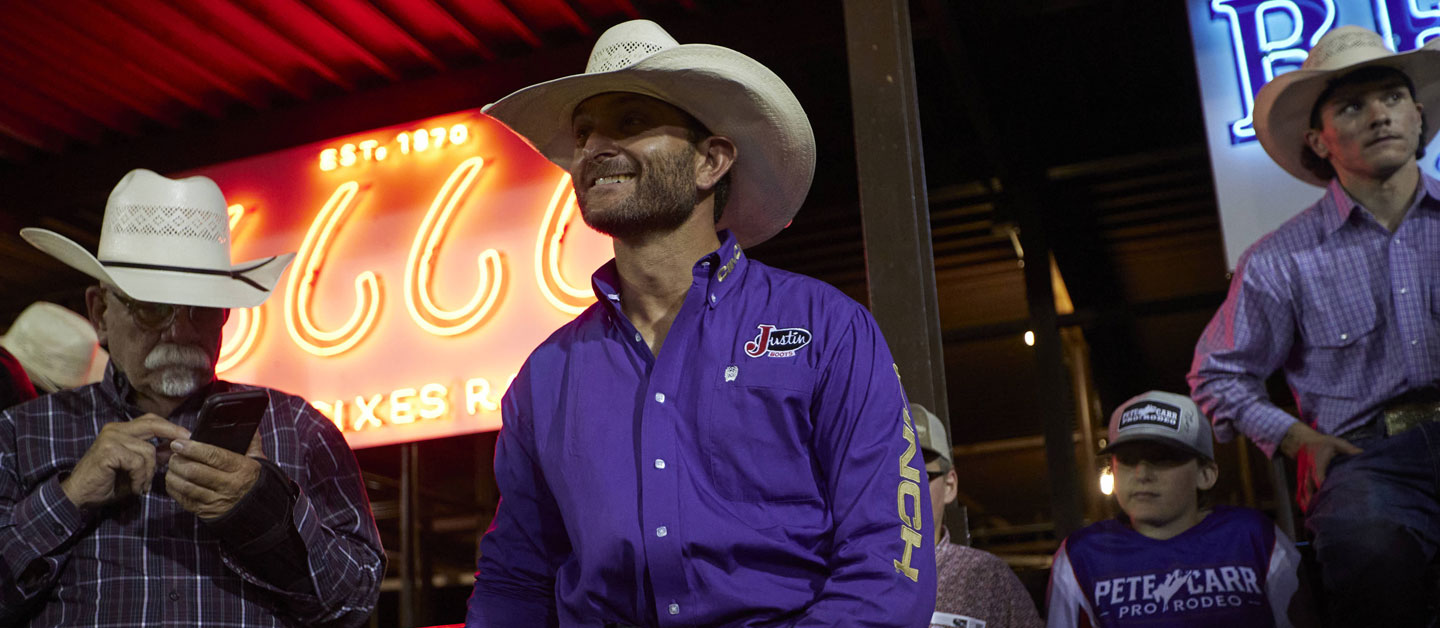 Dustin Boquet standing on the bucking chutes getting ready to ride.